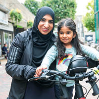 Naeema and her daughter smiling next to a bike